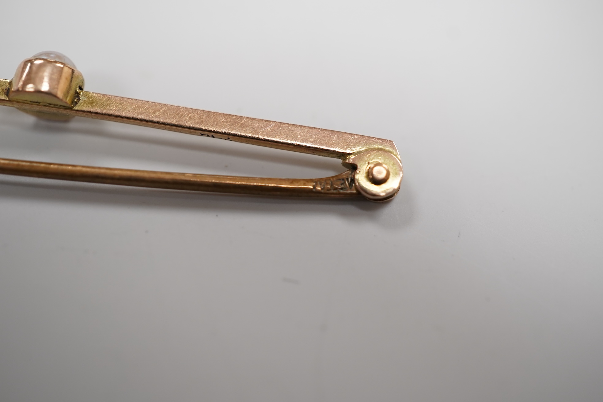 A cased early 20th century 9ct and single stone split pearl set bar brooch, 42mm and a white metal coin bracelet.